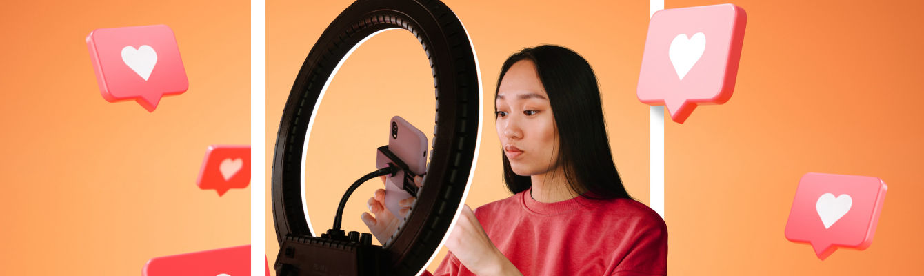 Female content creator adjusting her phone in a ring light, with floating Instagram-like heart icons around her, set against an orange background.