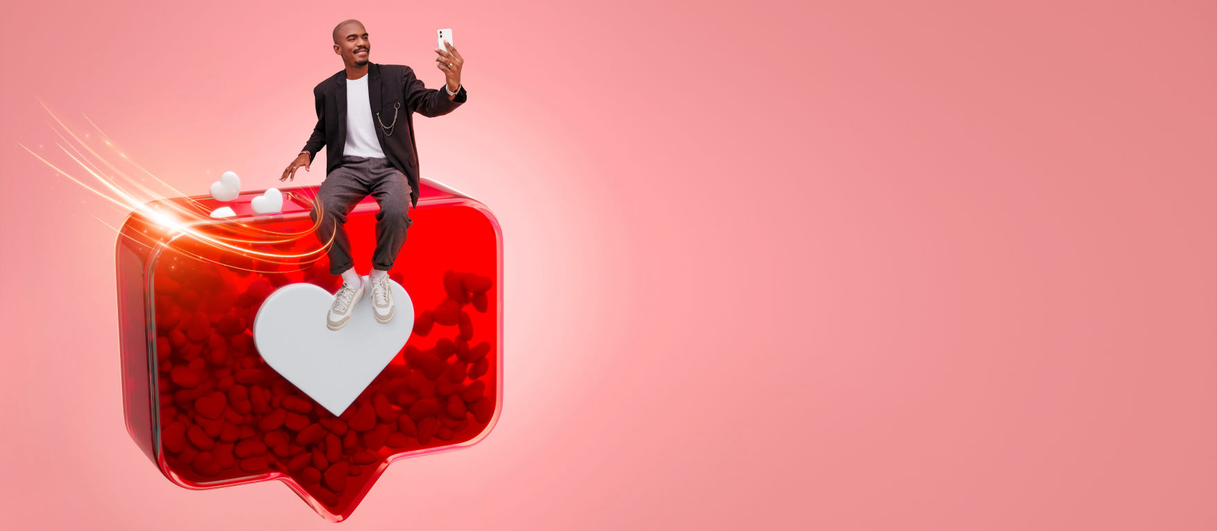 Man sitting on a large 3D Instagram-like icon with a white heart symbol, taking a selfie against a pink background with floating heart elements